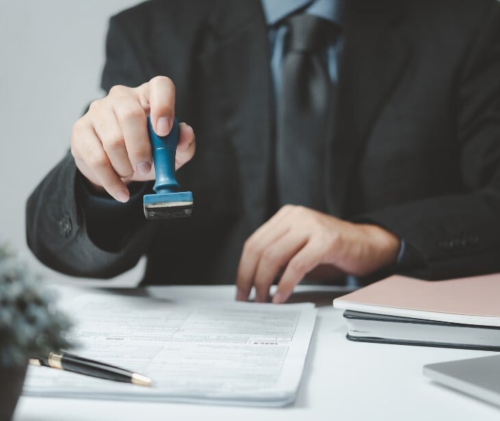 Image of an immigration officer stamping a file. 