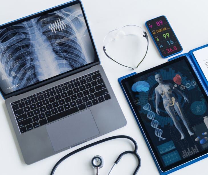 laptop with lung xray, tablet with body scan and stethoscope on surface