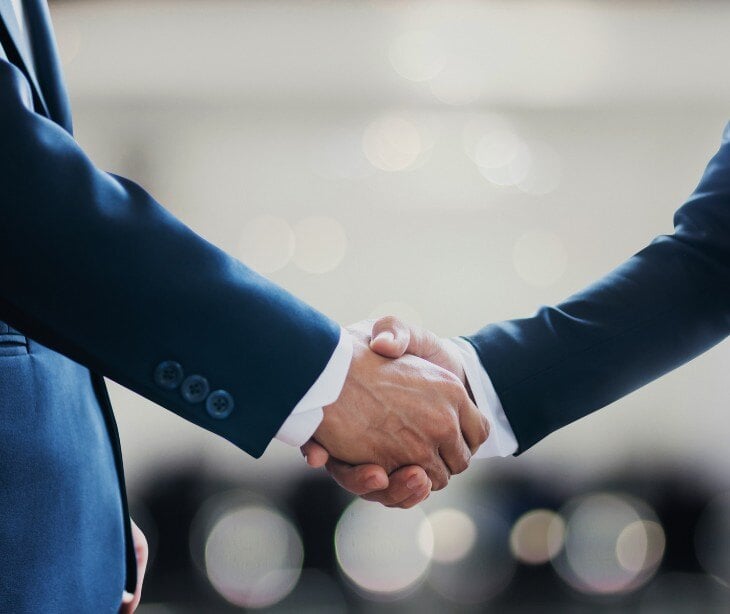 Image of two people in suits shaking hands.