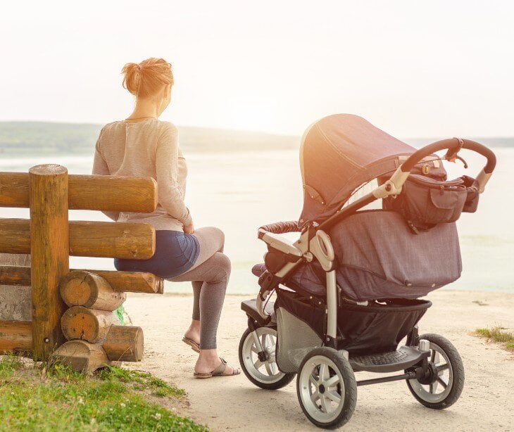 Image of woman sitting next to a stroller. 