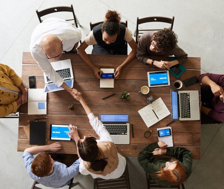 Image of several people on computers in a meeting. 