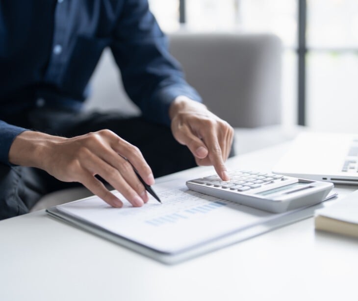 Image of someone taking notes and using a calculator. 