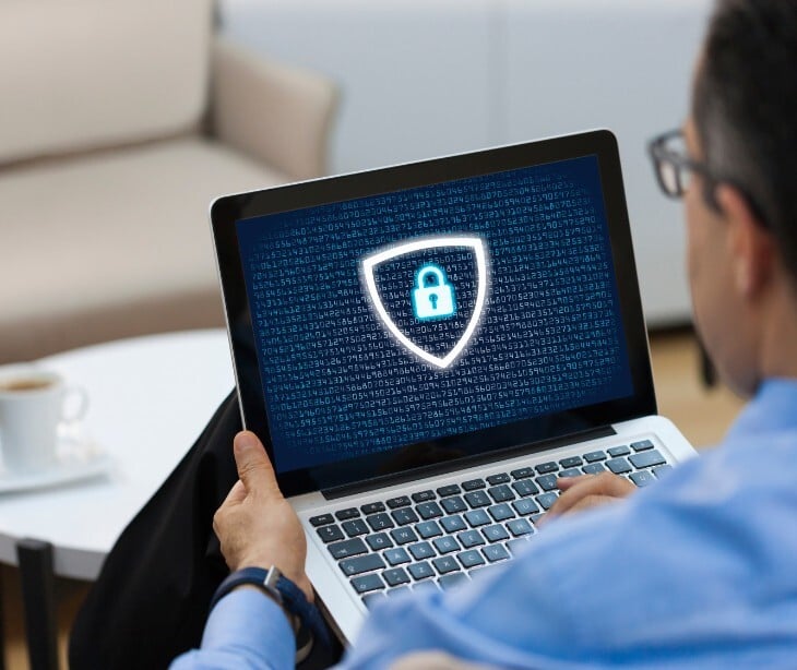 Image of someone looking at a computer with a shield on it. 