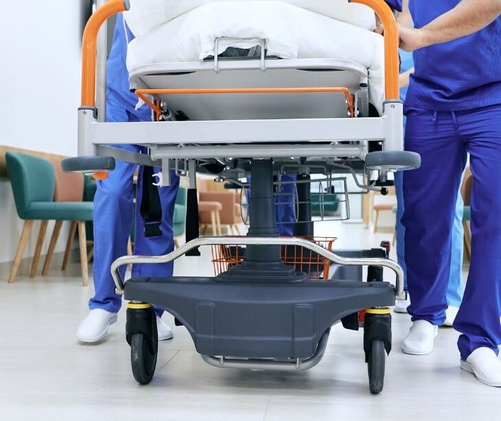 Image of someone on a stretcher near a hospital. 