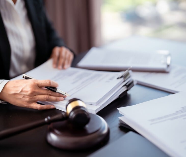 Image of someone signing paperwork near a gavel. 