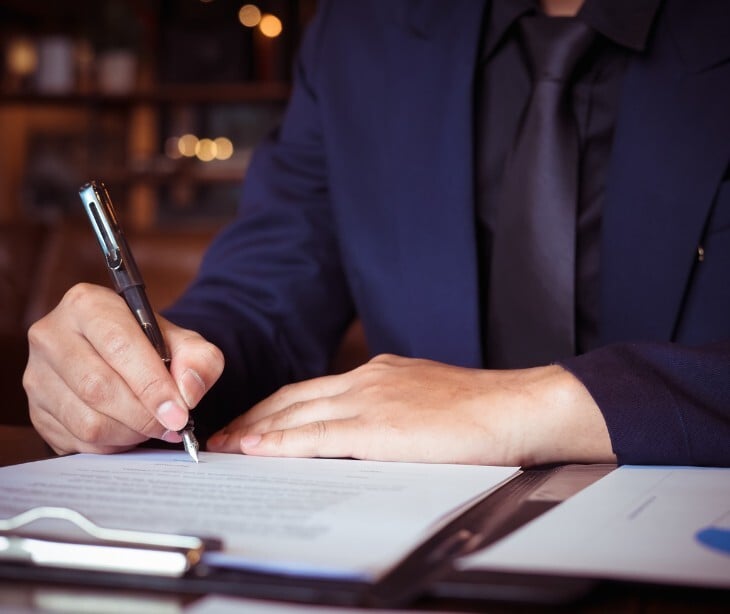 Image of an individual signing a contract. 