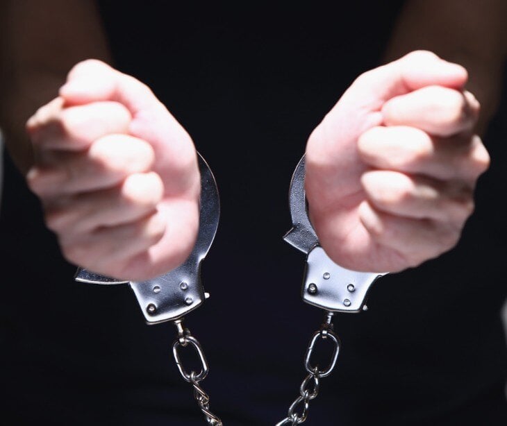 Image of person holding up cuffed hands.