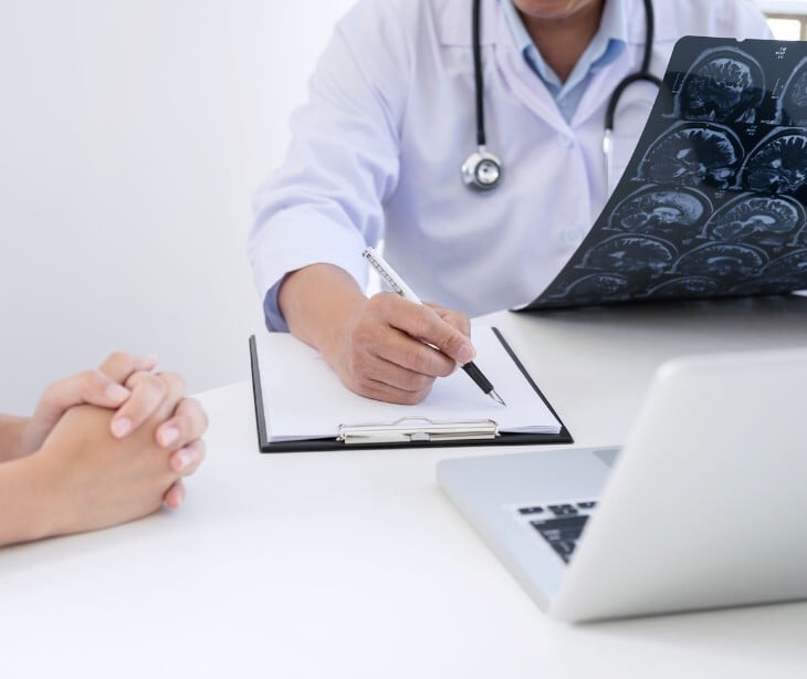 Image of a doctor looking at brain scans while talking to a patient. 
