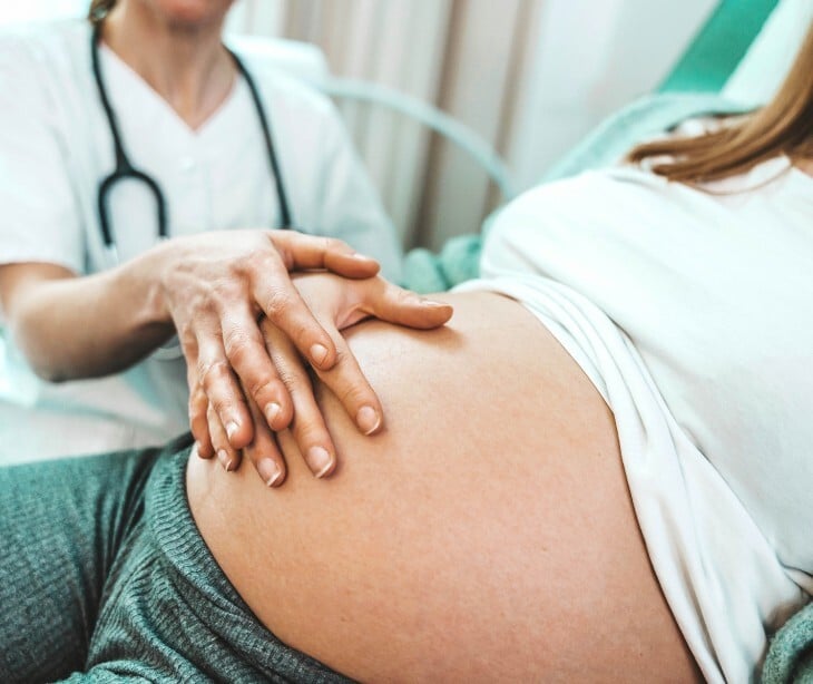 Image of a doctor touching a pregnant woman's stomach. 