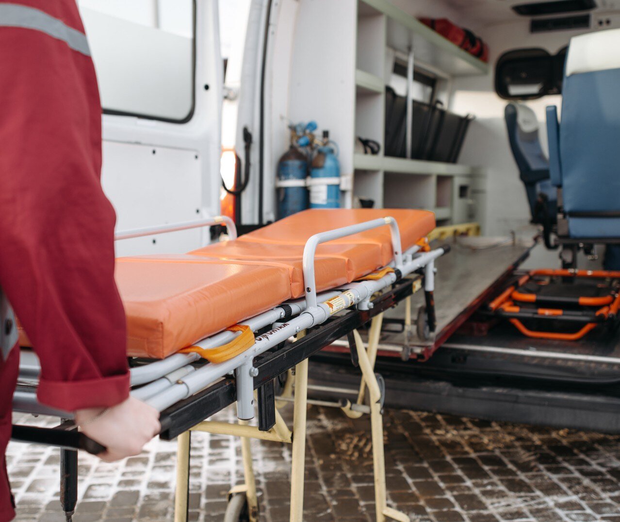 Image of a gurney being loaded into an ambulance. 