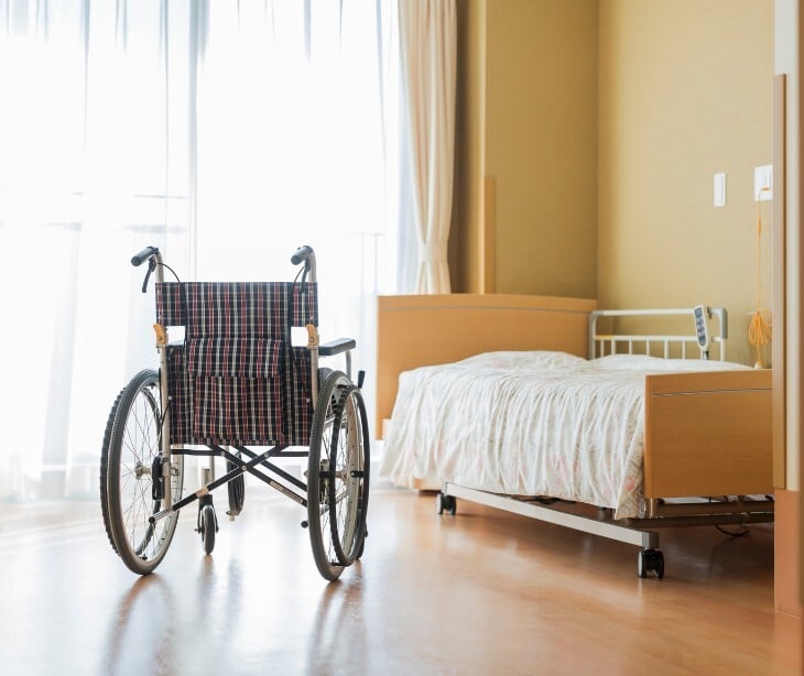 Image of a wheelchair and bed in a nursing home. 