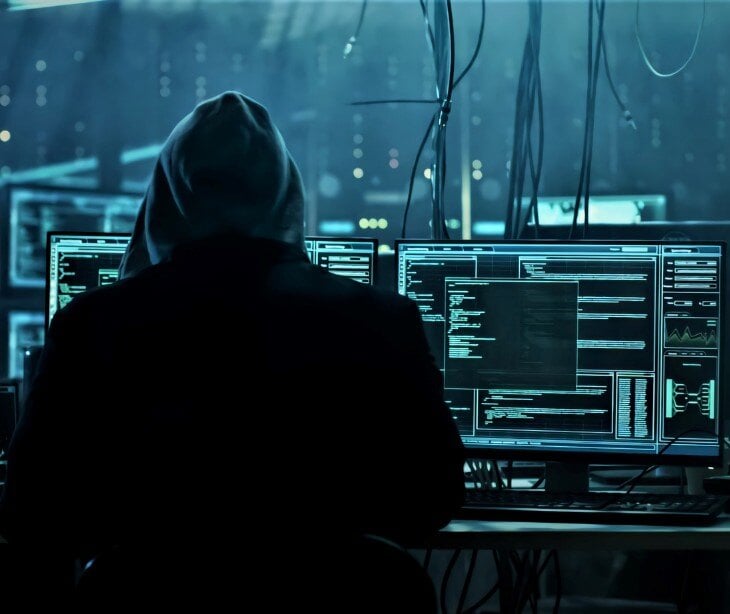 Graphic of person in hoodie on a computer for blog post on social engineering threats in healthcare