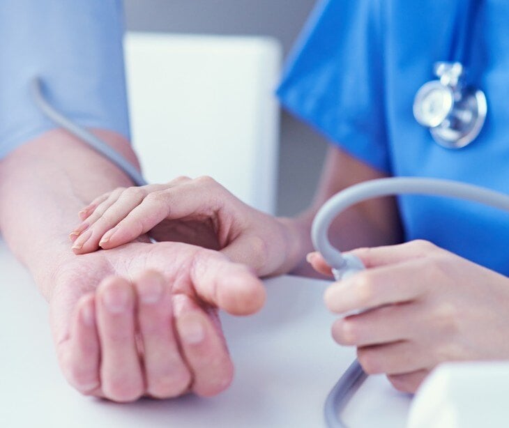 Image of doctor checking the pulse of a patient for a blog about HIPAA compliance risks during mass health screenings