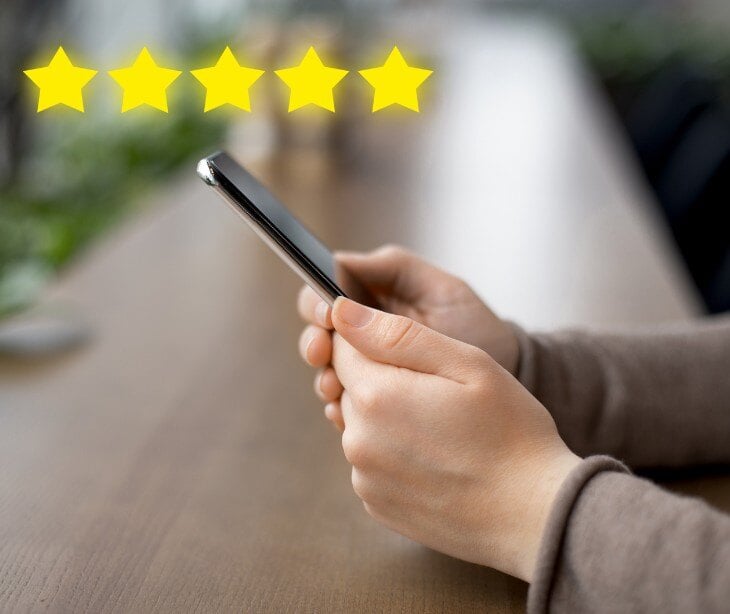 Image of someone holding a phone and stars to signify a review for blog about How psychiatrists should respond to negative reviews