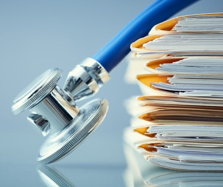 Image of multiple folders of records with a stethescope. 