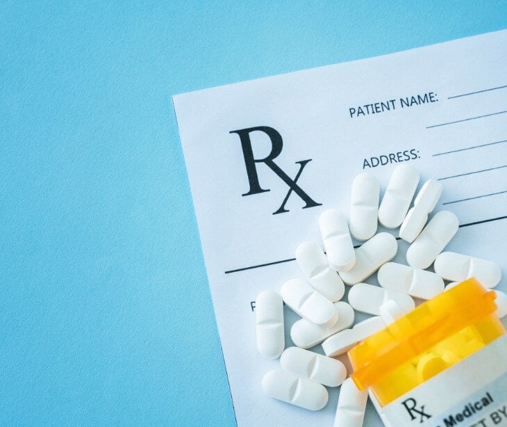 Image of a pill bottle near a paper for giving a prescription.