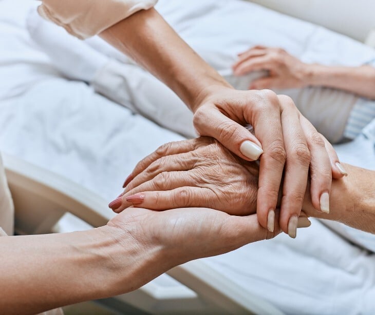Image of someone holding an elderly person's hand. 