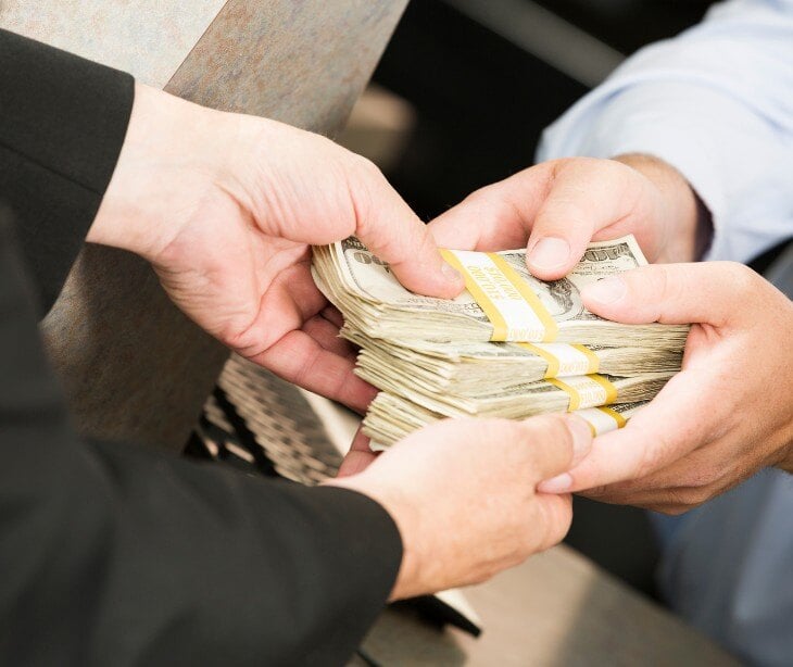 Image of someone handing cash to someone else.