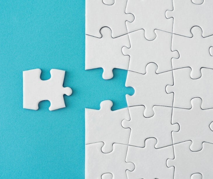Image of white puzzle piece fitting into a large puzzle.