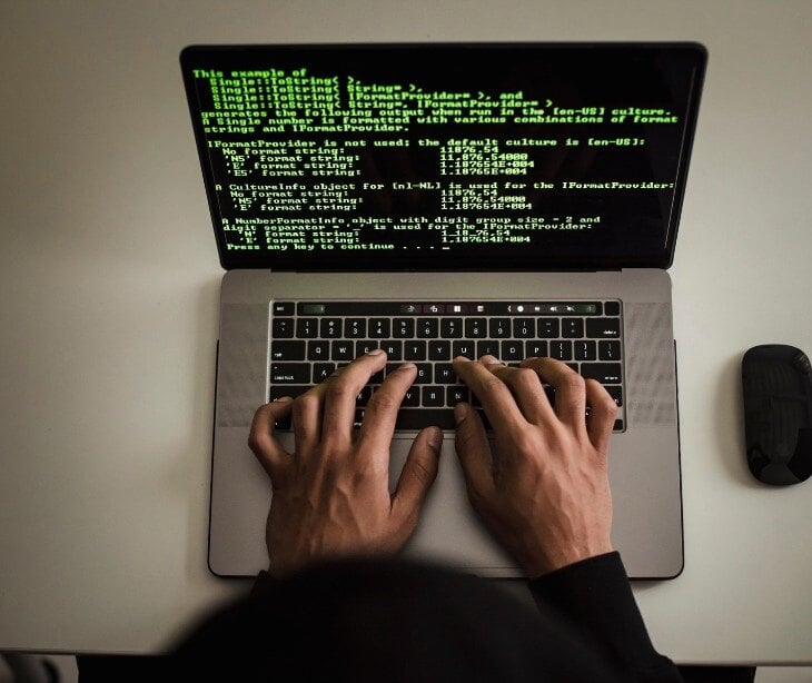 Image of someone typing green code on a laptop.