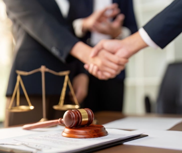 Image of someone shaking hands over a table with paperwork.